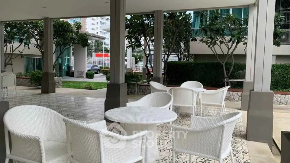 Chic outdoor seating area with modern white furniture and lush greenery, perfect for relaxation.