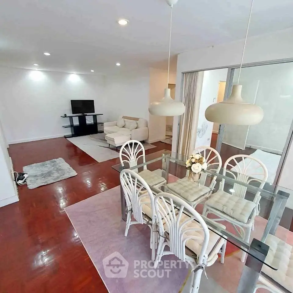 Spacious living and dining area with elegant glass table and cozy seating, perfect for modern living.