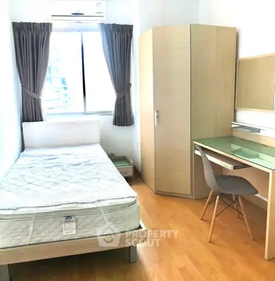 Cozy bedroom with single bed, wardrobe, and study desk in bright apartment.