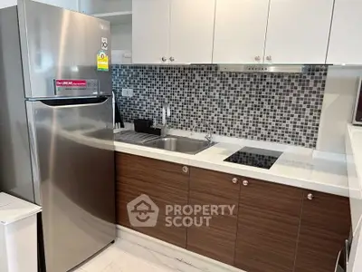 Modern kitchen with sleek cabinetry and stainless steel fridge in a stylish apartment.