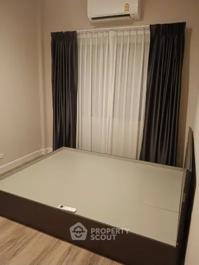Spacious and modern bedroom with elegant dark curtains, air conditioning, and sleek wooden flooring, awaiting your personal touch.