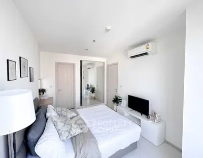 Modern bedroom with minimalist decor, featuring a comfortable bed, air conditioning, and a sleek TV setup.