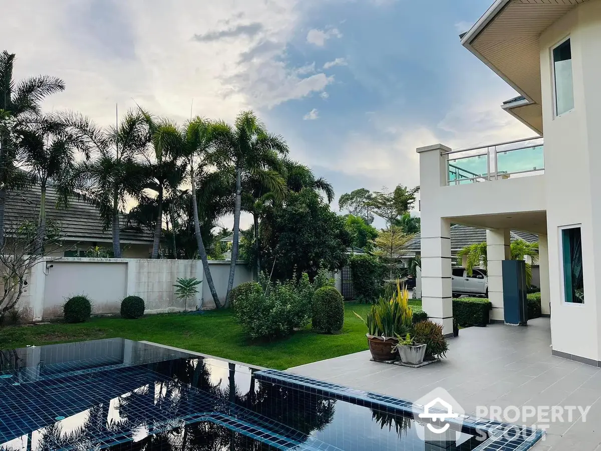 Luxurious modern home with a sparkling pool and manicured garden, featuring lush greenery and a spacious outdoor entertaining area.