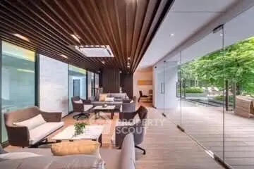 Luxurious modern living room with floor-to-ceiling glass doors opening to a lush garden view.