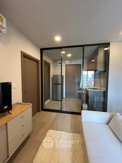Modern living room with glass partition and compact kitchen in urban apartment