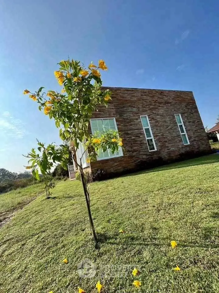 Charming modern home with stone facade and lush green lawn, perfect for serene living.