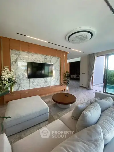 Luxurious living room with modern decor and pool view, featuring elegant marble accents and plush seating.