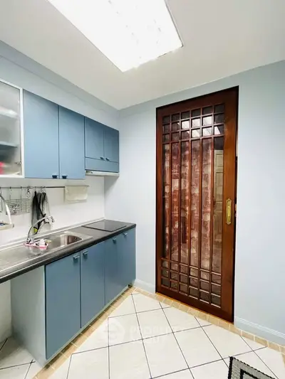 Modern kitchen with blue cabinets and wooden sliding door, featuring sleek design and efficient layout.