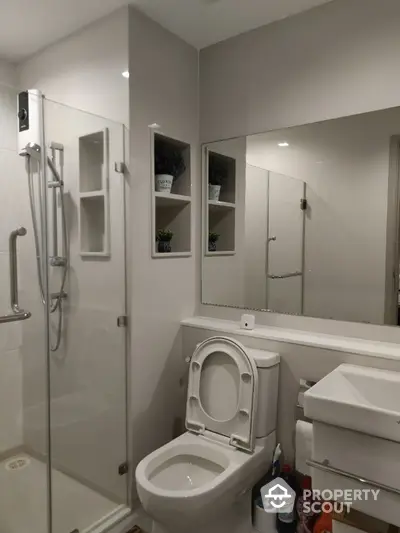 Modern bathroom with glass shower and sleek fixtures in contemporary home.