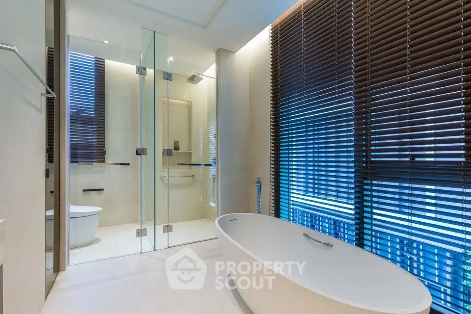 Luxurious modern bathroom with freestanding bathtub and glass shower enclosure.