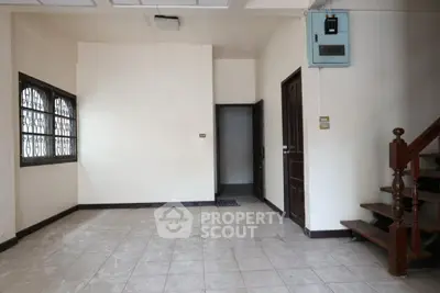 Spacious unfurnished room with tiled floor and wooden staircase, ideal for customization.