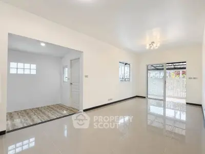 Spacious modern living room with glossy tiled floors and ample natural light.