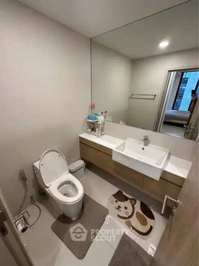 Modern bathroom with sleek fixtures and large mirror in contemporary apartment.