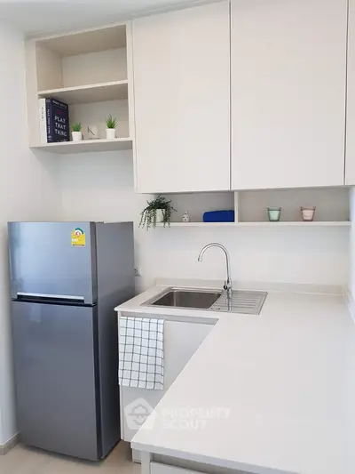 Modern kitchen with sleek cabinetry and stainless steel fridge in a compact layout.