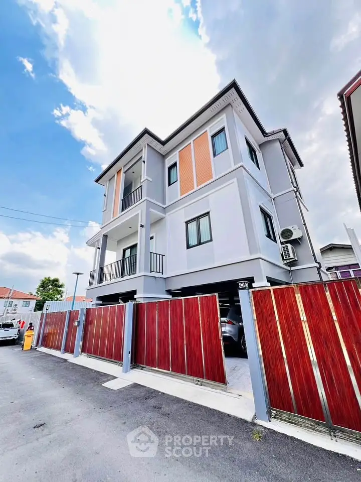 Modern three-story house with sleek design and gated entrance, perfect for family living.
