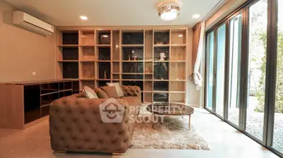 Luxurious living room with elegant sofa, large windows, and built-in shelving for a sophisticated ambiance.