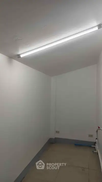Minimalist small room with white walls and fluorescent lighting, ideal for storage or utility use.