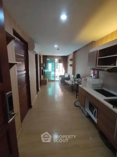 Modern apartment interior with open layout and balcony view, featuring sleek kitchen and cozy living area.