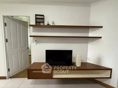 Modern living room with sleek wooden shelves and TV unit, minimalistic design.