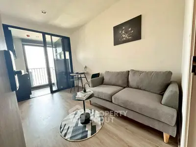Modern living room with cozy gray sofa and stylish decor, featuring a balcony view.