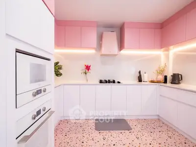 Modern kitchen with pink cabinets and terrazzo floor, featuring sleek appliances and open layout.