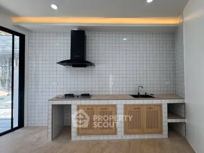 Modern kitchen with sleek gas stove and stylish cabinetry in a bright, tiled interior.