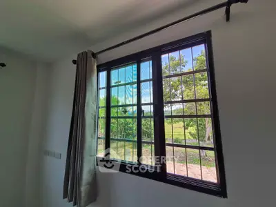 Bright room with large window offering scenic garden view, perfect for natural light lovers.