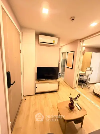 Modern living room with wooden flooring, TV, and air conditioning in a cozy apartment setting.