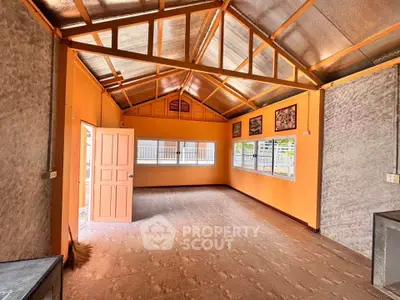 Spacious open-plan room with high ceilings and large windows, perfect for versatile living or workspace.