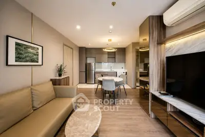 Modern living room with open kitchen, stylish decor, and cozy seating area.