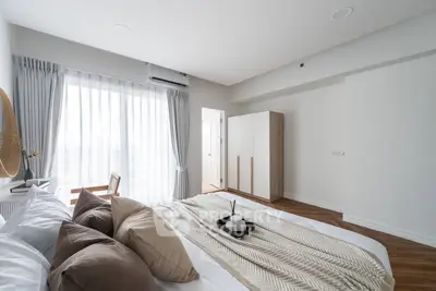 Spacious bedroom with modern decor and large window offering natural light