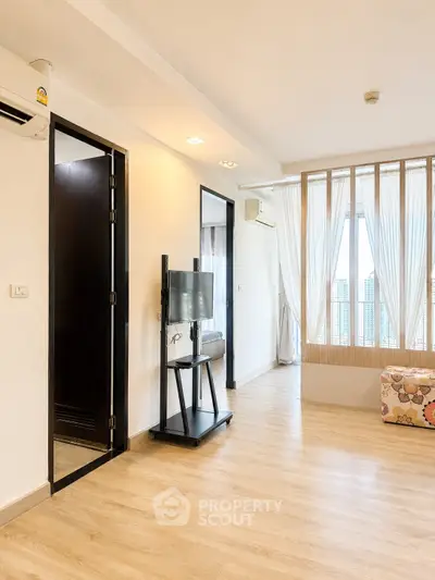 Spacious living room with modern decor and large windows offering city views.