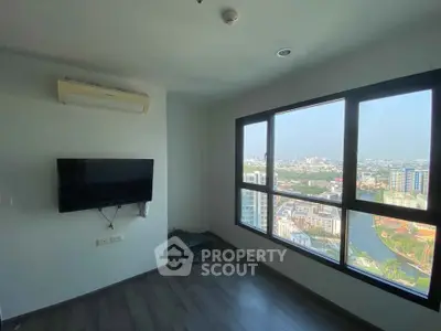 Modern living room with large windows offering stunning city views, featuring a wall-mounted TV and air conditioning.