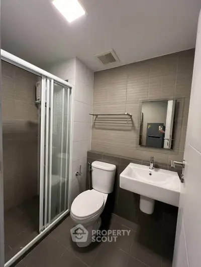 Modern bathroom with shower, toilet, and sink in sleek design.