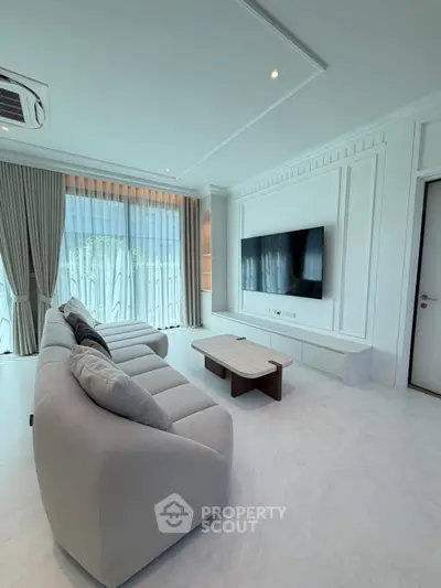 Spacious modern living room with large TV and elegant furnishings, perfect for relaxation and entertainment.