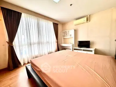 Spacious bedroom with natural light, featuring a cozy bed, air conditioning, and modern furnishings.