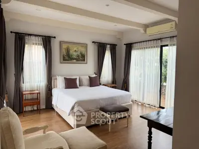 Spacious bedroom with elegant decor and large windows offering natural light.