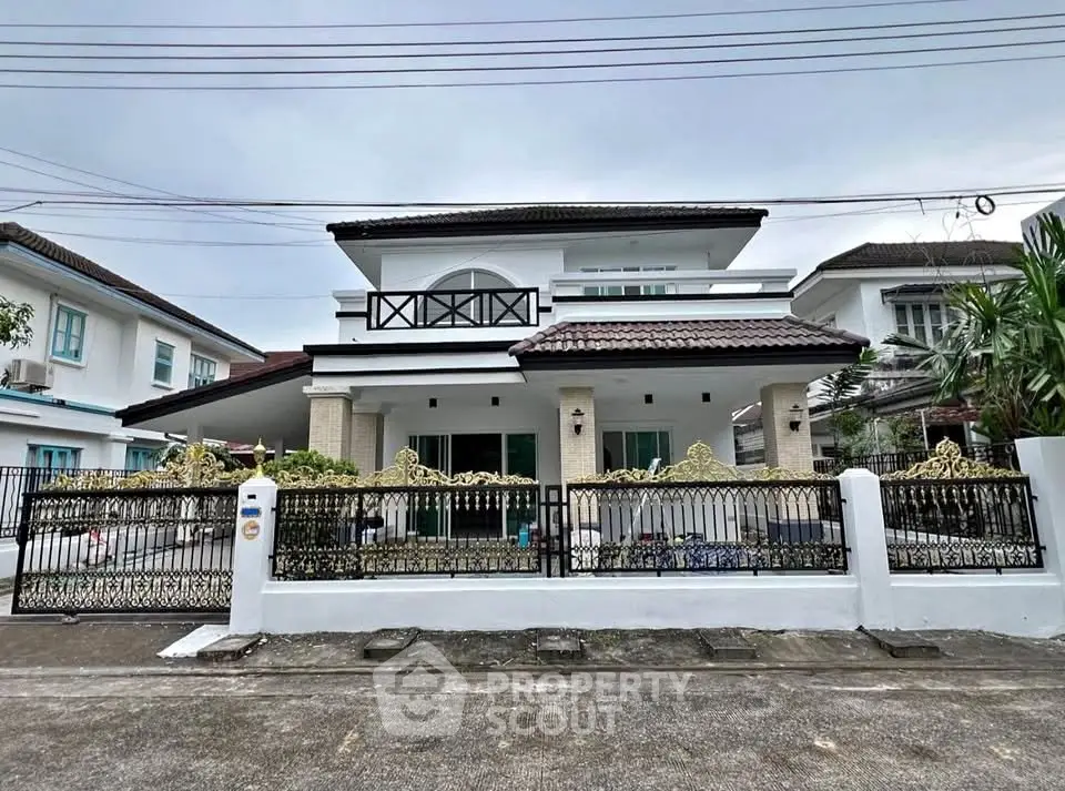 Elegant two-story house with ornate fence and spacious balcony in a serene neighborhood.