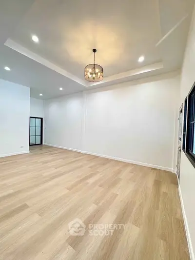 Spacious empty room with modern lighting and wooden flooring
