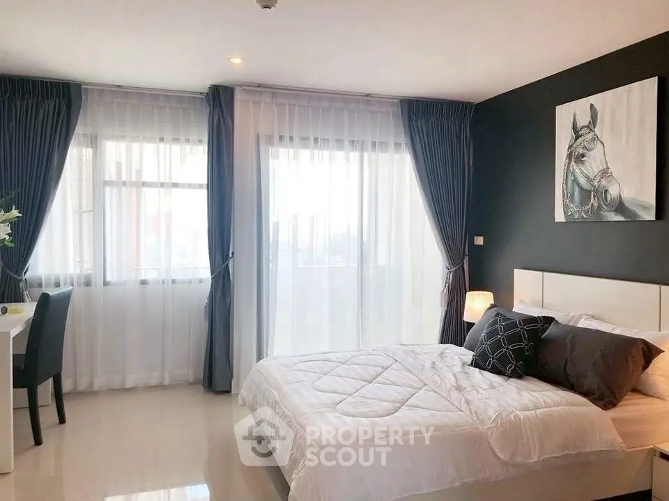 Spacious bedroom with modern decor and large windows for natural light.