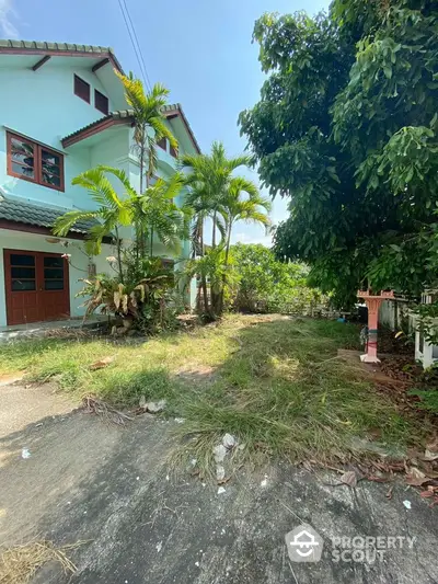 Charming two-story home nestled among lush greenery with a spacious front yard, offering a serene tropical living experience.