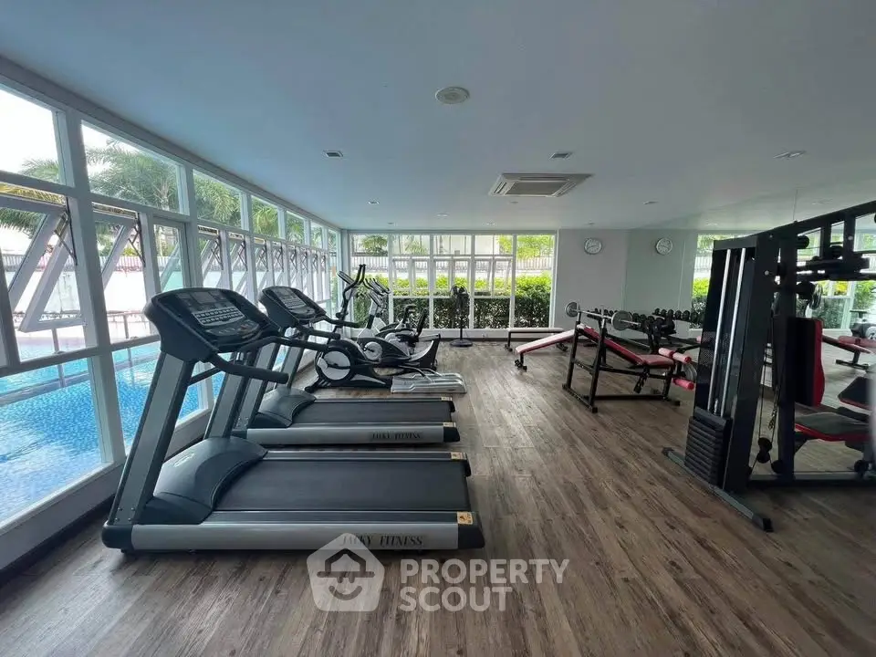 Modern gym with treadmills and weightlifting equipment overlooking a pool, perfect for fitness enthusiasts.