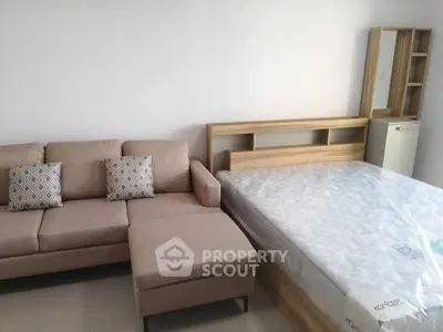 Modern bedroom with stylish beige sofa and wooden bed frame, perfect for cozy living.