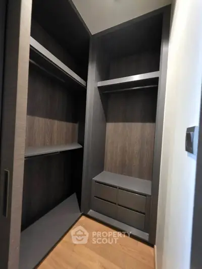 Spacious walk-in closet with modern dark wood finish and ample storage space.