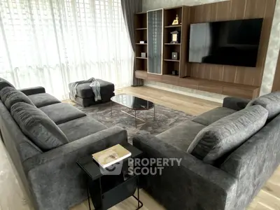 Luxurious living room with plush gray sofas, modern entertainment center, and floor-to-ceiling windows.