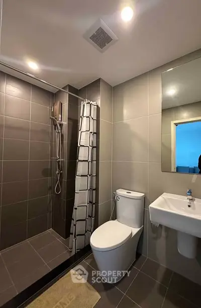 Modern bathroom with sleek design, featuring a shower, toilet, and sink in a contemporary setting.