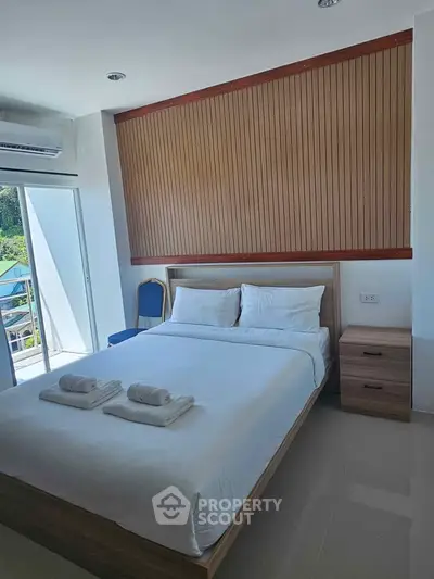Modern bedroom with large window and natural light, featuring a comfortable bed and stylish decor.