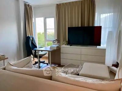 Modern living room with cozy sofa, flat-screen TV, and study desk by the window.