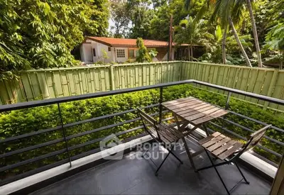 Charming balcony with lush garden view and cozy seating area, perfect for relaxation.