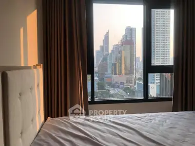 Modern bedroom with city view, featuring large window and elegant curtains.